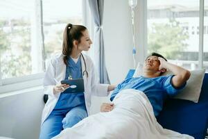 caucásico médico sonriente tomar cuidado de un joven paciente en hospital. simpático enfermero o terapéutico tratar cliente profesional médico Servicio concepto. foto