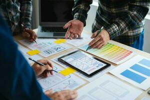 Close up view of UI developer team brainstorming on their project with laptop, smartphone and digital tablet. Creative digital development agency. photo