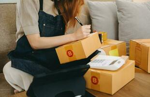 Woman hand using a laptop, smartphone and tablet and writing notebook at the office of her business online shopping. In home photo