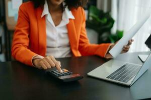 Businesswoman hands working with finances about cost and calculator and laptop with tablet, smartphone at office photo