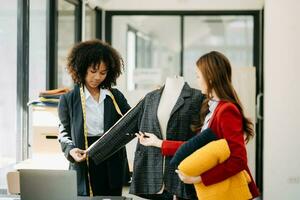 Diverse female fashion designers at work with tailor centimeters on necks and holds tablet and smartphone. independent creative design business. photo