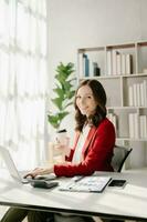 Confident Asian woman with a smile standing holding notepad and tablet at the modern office. photo