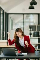 Asian business woman are delighted and happy with the work they do on their tablet, laptop and taking notes at the office. photo