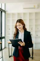 Confident business expert attractive smiling young woman holding digital tablet  on desk in creative office. photo