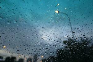 rain drops on glass with cityscape background, rainy season concept. photo