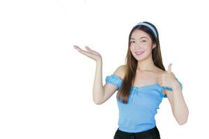 Young beautiful Asian woman in a blue shirt is acting thumb up as a good symbol and another hand shows as presenting something on white the background. photo