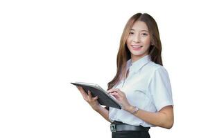 retrato de linda joven asiático tailandés niña estudiante en un uniforme es en pie sonriente felizmente y con confianza mientras utilizando un tableta aislado en blanco antecedentes. foto