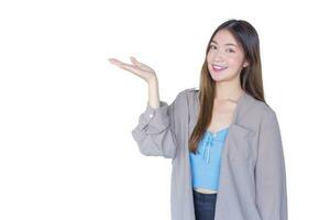 hermosa joven asiático mujer largo marrón pelo en un azul camisa es interino mano muestra como presentación alguna cosa aislado en blanco antecedentes. foto
