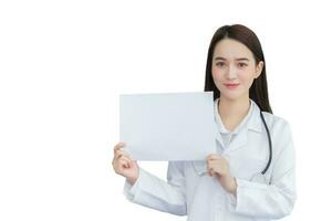 Professional young Asian woman doctor who wears medical coat holds and shows white paper to present something in healthcare concept isolated on white background. photo