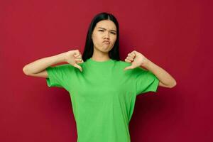 Charming young Asian woman green t-shirt gestures with his hands red background unaltered photo