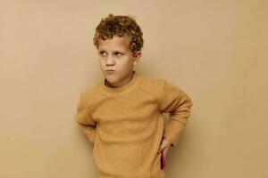 curly boy in a beige sweater posing fun childhood unaltered photo