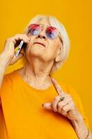 smiling elderly woman happy lifestyle in yellow t-shirts with phone close-up emotions photo