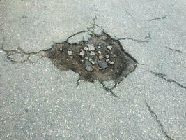 The texture of cracked old asphalt. large pothole in country asphalt road photo