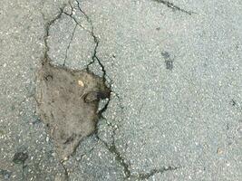 The texture of cracked old asphalt. large pothole in country asphalt road photo