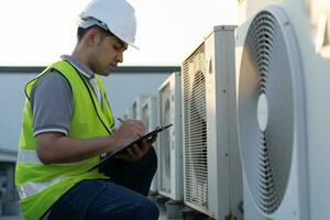 Asian maintenance engineer works on the roof of factory. contractor inspect compressor system and plans installation of air condition systems in construction. Checklist, inspector, control photo