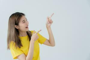 Portrait asian beautiful girl pointing blank space isolated background. Happy woman pointing on something. young female standing pointing finger sideways, billboard, introduction, advertisement photo