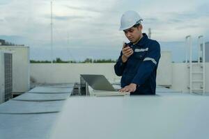 Asian maintenance engineer working on color background, contractor inspect compressor system and plans installation of air condition systems in construction. technology, walky talky, maintenance photo