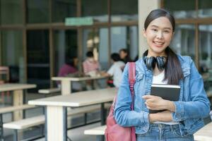 Beautiful student asian woman with backpack and books outdoor. Smile girl happy carrying a lot of book in college campus. Portrait female on international Asia University. Education, study, school photo