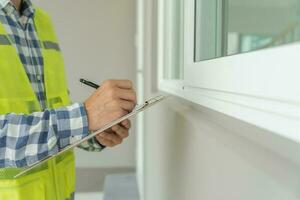 el inspector o ingeniero está inspeccionando la construcción y el aseguramiento de la calidad de la nueva casa usando una lista de verificación. ingenieros o arquitectos o contratistas trabajan para construir la casa antes de entregársela al propietario foto