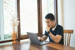 negocio Lanza libre empresario hombre con blanco auricular trabajando mecanografía teclado en ordenador portátil y en de madera mesa a el café café tienda. negocio tecnología concepto. foto