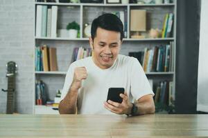 Freelance man working with laptop and mobile successful cheerful, sitting at wooden table. Pleasant happy man communicating in social network, conferrence vdo call. Business working concept. photo