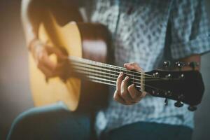 mujer jugando acústico guitarra sentado en público parque en un relajado. mujer practicando jugando guitarra debajo un árbol felizmente. foto