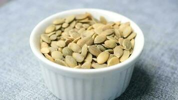 Pumpkin seeds in a small bowl on black background video