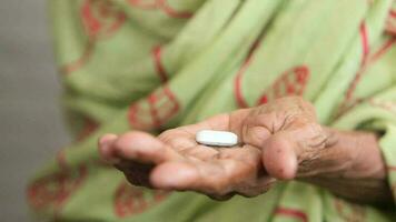 A single medical pill on palm of senior woman hand video