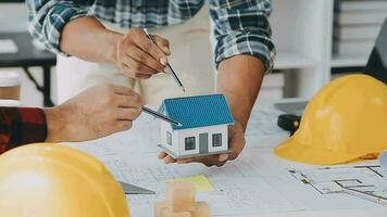 equipe do construção trabalhadores vestindo protetora capacetes e coletes discutindo projeto detalhes com executivo Supervisor em pé às mesa com plantas, Ferramentas e computador portátil em isto video