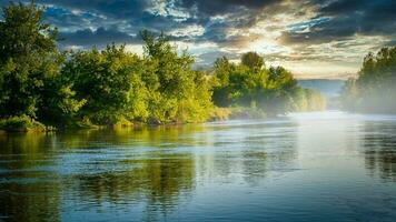 río con arboles a puesta de sol foto