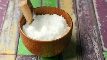 Hand pick Coarse salt i with a spoon from a bowl on table video