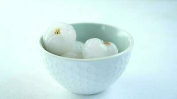 Lychee fruits drops in a bowl on white background video