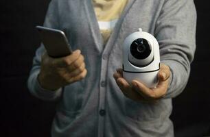 Woman holding white IP camera. Very popular for security purposes. photo