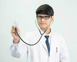 Asian man student scientist or doctor one person, wearing a white gown, standing, looking and smiling, white background with a stethoscope auscultating the heart around his neck. photo