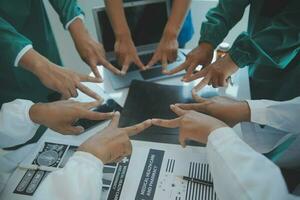 Mature doctors and young nurses stacking hands together at hospital. Close up hands of medical team stacking hands. Group of successful medical doctors and nurses stack of hands. photo