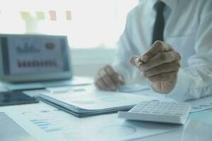 Close up businessman hand using calculator and working with laptop calculate about finance accounting at coffeeshop outdor.finance accounting concept photo