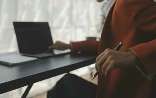 Asian Business woman using calculator and laptop for doing math finance on an office desk, tax, report, accounting, statistics, and analytical research concept photo