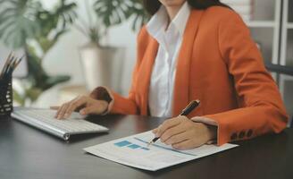 Asian Business woman using calculator and laptop for doing math finance on an office desk, tax, report, accounting, statistics, and analytical research concept photo
