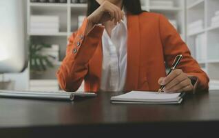 Asian Business woman using calculator and laptop for doing math finance on an office desk, tax, report, accounting, statistics, and analytical research concept photo