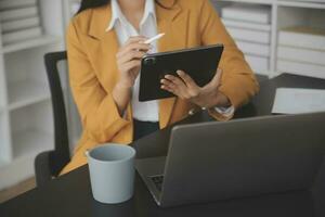 Asian Business woman using calculator and laptop for doing math finance on an office desk, tax, report, accounting, statistics, and analytical research concept photo
