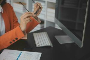 Asian Business woman using calculator and laptop for doing math finance on an office desk, tax, report, accounting, statistics, and analytical research concept photo