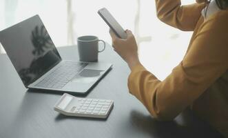 Asian Business woman using calculator and laptop for doing math finance on an office desk, tax, report, accounting, statistics, and analytical research concept photo