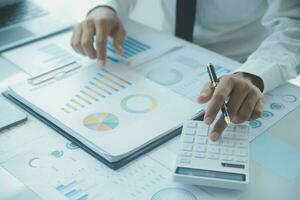 Close up businessman hand using calculator and working with laptop calculate about finance accounting at coffeeshop outdor.finance accounting concept photo