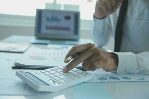 Close up businessman hand using calculator and working with laptop calculate about finance accounting at coffeeshop outdor.finance accounting concept photo