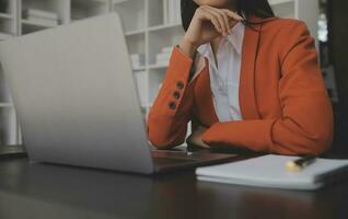 Asian Business woman using calculator and laptop for doing math finance on an office desk, tax, report, accounting, statistics, and analytical research concept photo