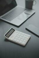 Asian Business woman using calculator and laptop for doing math finance on an office desk, tax, report, accounting, statistics, and analytical research concept photo