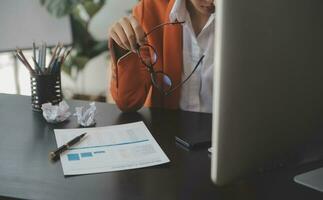 Asian Business woman using calculator and laptop for doing math finance on an office desk, tax, report, accounting, statistics, and analytical research concept photo
