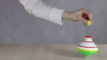 Hand moving a colorful spinning top on a table. Closeup video