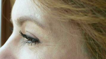 Close up Caucasian woman beside the window looking outside observing with a smile video