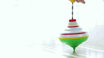 Colorful spinning top moving on a table with transparent curtain on the background. video